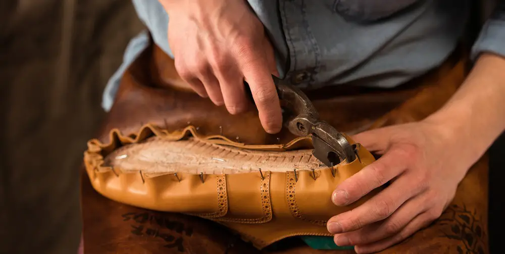 bootmaker sitting in workshop making shoes