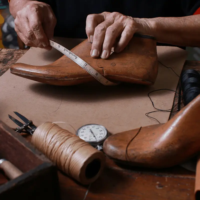 a cobbler measuring a shoe mold