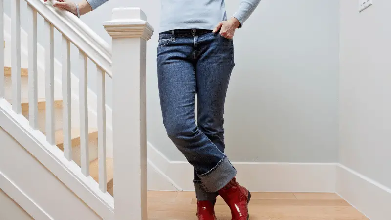 Person wearing a pair of boots on their staircase.