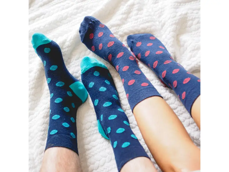 couple wearing socks sitting on a bed